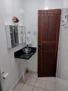 a bathroom with a sink and a wooden door at Meu Oca in Boa Vista
