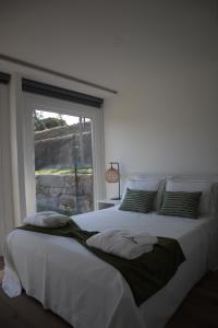 Schlafzimmer mit einem großen weißen Bett und einem Fenster in der Unterkunft Refugio D Alecrim in Paredes
