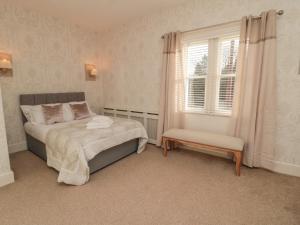 a bedroom with a bed and a chair and a window at Dovecote Cottage in Newcastle upon Tyne