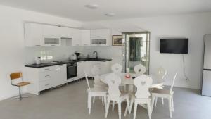 cocina con armarios blancos, mesa y sillas en Haus mit Garten bei Wien en Langenzersdorf