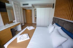 - une chambre dotée d'un grand lit avec des draps et des oreillers blancs dans l'établissement Vinea Resort, à Durrës
