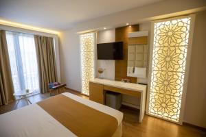 a bedroom with a bed and a desk and a television at Vinea Resort in Durrës