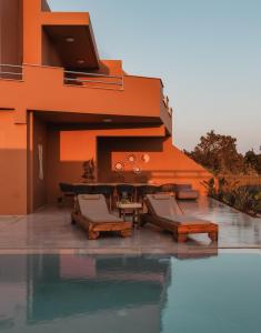 an orange building with chairs and a swimming pool at Aerope SeaView Villa, a Family Retreat, By ThinkVilla in Koutsounari