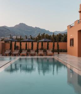 una piscina con sillas y sombrillas en un edificio en Aerope SeaView Villa, a Family Retreat, By ThinkVilla, en Koutsounari