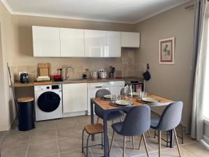 Una cocina con gabinetes blancos y una mesa y sillas. en Les jardins de la Capelière, en Méounes-lès-Montrieux