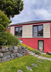 una casa roja con una pared de piedra delante de ella en Ferienhaus Conradshöh, en Ilmenau