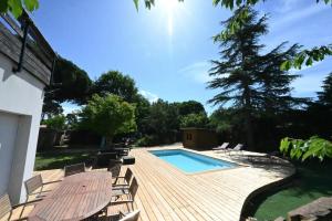 a wooden deck with a swimming pool and chairs at Villa Le Chêne Vert in Arès