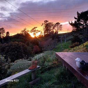 a wooden bench with a sunset in the background at Cosy Country Cottage on a Sunny Hill in New Plymouth