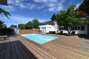 a backyard with a swimming pool and a wooden deck at Villa Le Chêne Vert in Arès
