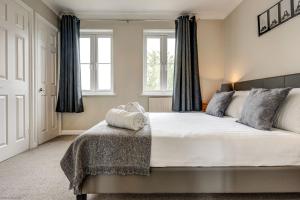 a bedroom with a large bed and two windows at The Didcot White House in Didcot