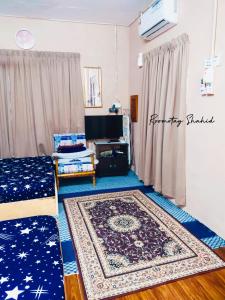 uma sala de estar com uma cama e um tapete em ROOMSTAY SHAHID HOU'ZE em Kangar