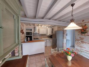 een keuken met een tafel en een keuken met een koelkast bij Gîte l'Ostalet de Sarron à Brax, Lot et Garonne in Brax