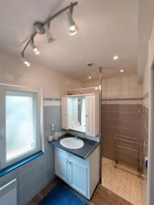 een badkamer met een wastafel, een spiegel en een douche bij Gîte l'Ostalet de Sarron à Brax, Lot et Garonne in Brax