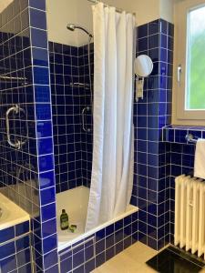 a blue tiled bathroom with a shower with a white curtain at Schönes Zimmer in guter Lage in Aalen/Unterkochen in Unterkochen