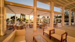 un patio al aire libre con mesas, sillas y mesa en Golden Coast Beach Hotel, en Protaras