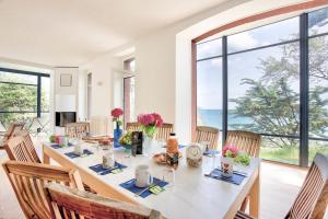 ein Esszimmer mit einem langen Tisch mit Stühlen und Fenstern in der Unterkunft Le Cottage - Maison avec vue imprenable in Saint-Cast-le-Guildo