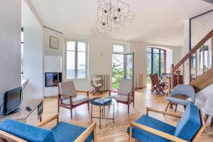 een woonkamer met blauwe stoelen en een tv bij Le Cottage - Maison avec vue imprenable in Saint-Cast-le-Guildo