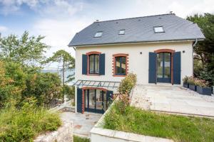 ein weißes Haus mit roten Fenstern und einem Dach in der Unterkunft Le Cottage - Maison avec vue imprenable in Saint-Cast-le-Guildo