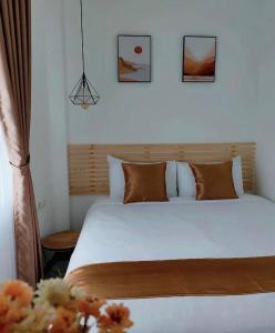 1 dormitorio con 1 cama con sábanas blancas y almohadas marrones en Omahku Homestay, en Borobudur