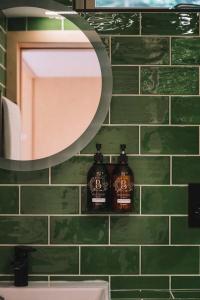 baño con espejo y pared de azulejos verdes en Mertrick en Forest Mill