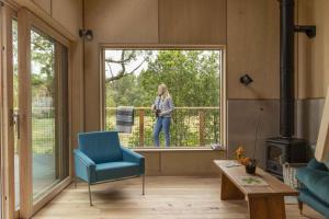 una donna in piedi su un balcone che guarda fuori da una finestra di Mertrick a Forest Mill