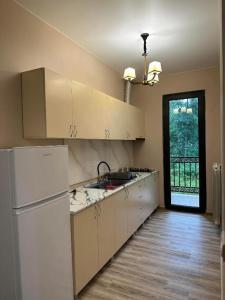 uma cozinha com armários brancos e um frigorífico branco em Lilus Apartament Shekvetili em Shekhvetili