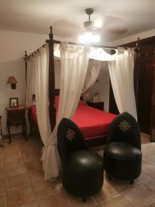 1 dormitorio con 1 cama con dosel y 2 sillas en Finca Marchequivir, en Bernia