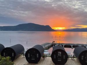 a view of a dock with the sun setting over the water at Sleeping barrel lodge, Smaken av Ryfylke in Hjelmeland