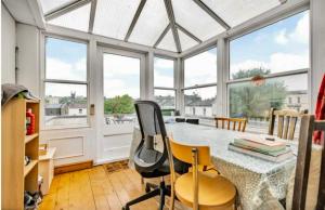 a dining room with a table and chairs and windows at 3 bed penthouse flat with conservatory & roof terrace - city views in Bristol