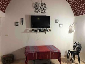 uma sala de estar com uma mesa e uma televisão na parede em Appartement MANEL em Mezraya