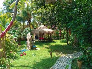 a garden with a grass hut and a path at UTOPIA in Gili Air