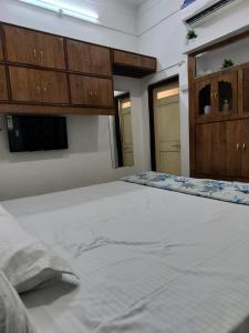 Cette chambre comprend un grand lit blanc et des placards en bois. dans l'établissement Ashutosh Homestay and Hotels, à Ujjain