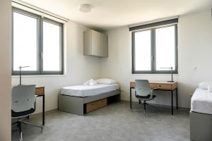 a room with a bed and desks and windows at Hostel 'SD Palacin' in Šibenik