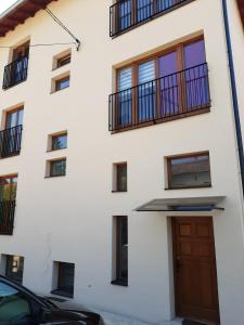Gornja Toplica的住宿－Ime Ruze apartmani Banja Vrujci，白色的建筑,设有棕色的门和阳台