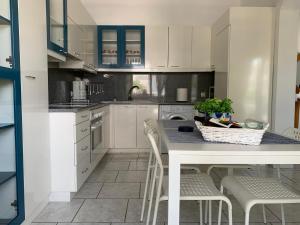 a kitchen with white cabinets and a table with chairs at Blue Maison in Paralia Katerinis