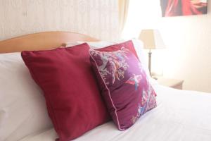 two red pillows sitting on top of a bed at Cleve Court Hotel in Paignton