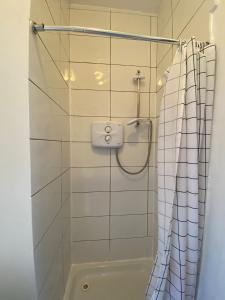 a bathroom with a shower with a white tiled wall at Sarsfield Hostel in Dublin