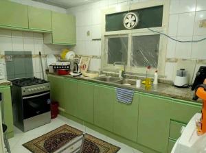 a kitchen with green cabinets and a sink and a window at Happy nights in Sharjah