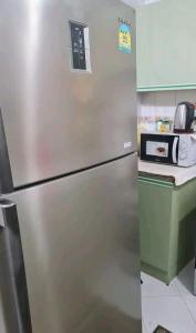 a stainless steel refrigerator in a kitchen with a microwave at Happy nights in Sharjah