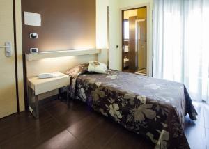 una camera d'albergo con letto, tavolo e specchio di Hotel Taormina a San Benedetto del Tronto