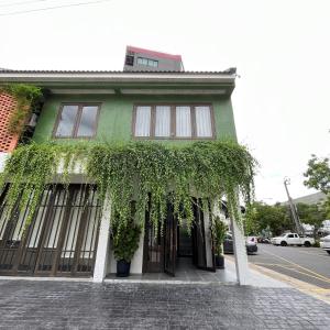 un edificio verde con hiedra creciendo a su alrededor en Homie Non - โฮมมี่ นนท์, en Ban Bang Khwang