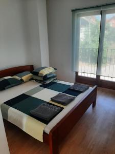 a large bed in a room with a large window at Ime Ruze apartmani Banja Vrujci in Gornja Toplica