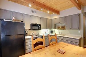 cocina con nevera negra y mesa de madera en Cozy Mountain Retreat with Private Jacuzzi, en Big Bear Lake
