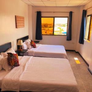 two beds in a room with a window at La Casa Baatsona Apts in Accra