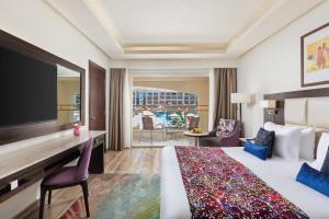 a hotel room with a bed and a desk with a television at Pickalbatros White Beach Resort - Hurghada in Hurghada