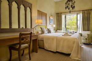 a bedroom with a bed and a desk and a mirror at Yewfield Vegetarian Guest house in Ambleside