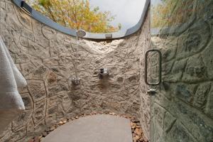 a bathroom with a stone wall with a shower at SaffronStays Sanvina Farm, Karjat in Karjat