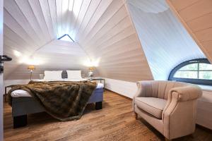 a attic bedroom with a bed and a chair at Bottengarn Boutique Guesthouse in Koguva