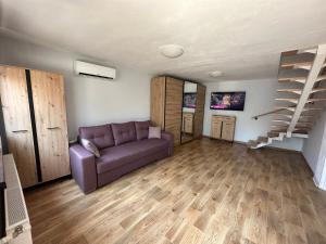 sala de estar con sofá púrpura y escalera en Luna's house, en Sibiu