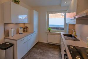 eine Küche mit weißen Schränken, einem Fenster und einem Waschbecken in der Unterkunft Charmante 3 Zimmer WHG mit Terrasse in Scharbeutz